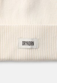 Berretto a coste bianco in maglia con risvolto e un piccolo etichetta tessuta con "DRYKORN" in testo nero. Texture morbida e design semplice.