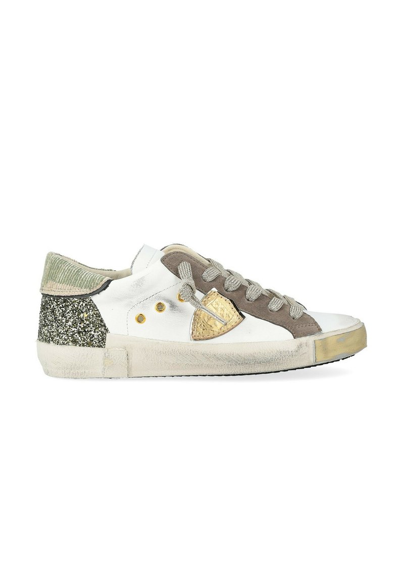 Sneaker bassa bianca con lacci grigi, dettagli in suede marrone, logo a scudo dorato, tallone glitter verde e suola logorata.