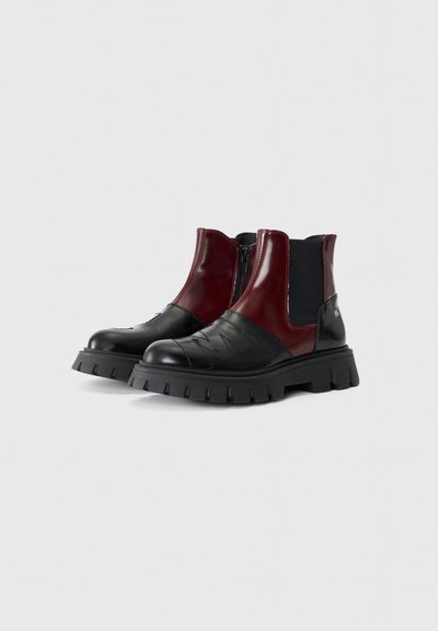 Svarta och vinröda ankelboots med en glänsande finish, elastiska sidopaneler och en kraftig texturerad sula med synliga mönster.