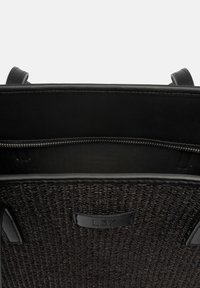 Zwarte geweven tote bag met gladde leren accenten, voorzien van een gestructureerde binnenkant en een ritsvak. Label L37 zichtbaar aan de binnenkant.