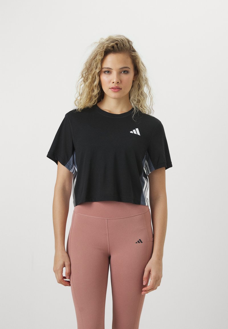 Svart cropped t-skjorte med korte ermer har en liten hvit Adidas-logo på brystet og kontrasterende grå sidelapper.