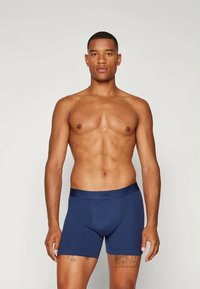 Boxer briefs azul-marinho com uma cinturilha elástica, apresentando um logótipo na parte da frente. O tecido parece suave e justo.