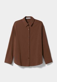 Camicia marrone a maniche lunghe con colletto strutturato, chiusura a bottoni e tessuto texturizzato con righe verticali. Orlo arrotondato e maniche aderenti.