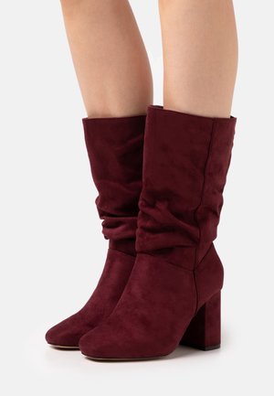 Bottes basses bordeaux au design décontracté, en matériau doux imitant le daim, avec un talon bloc et un bout arrondi.
