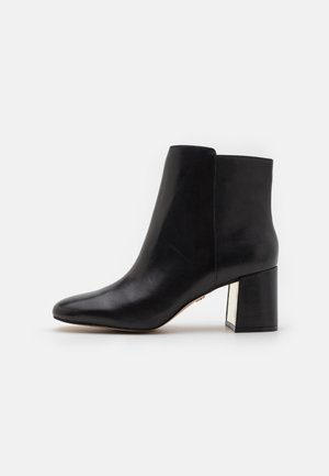 Schwarze Leder-Ankle Boots mit spitzer Zehenform, glatter Textur und einem klobigen, quadratischen Absatz mit metallischem Akzent.