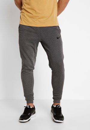 Jogging gris athlétique avec une coupe fuselée, doté d'une taille élastique et de poches latérales. Logo Nike noir sur la cuisse gauche.