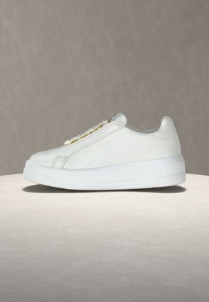 Fehér, alacsony szárú sneaker vastag talppal, arany fémfülekkel, finom "Love Moschino" márkajelzéssel az oldalon, bézs felületen kiemelve.