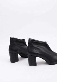 Black ankle boots made of smooth leather featuring a high block heel, rounded toe, and elastic sides for easy wear.