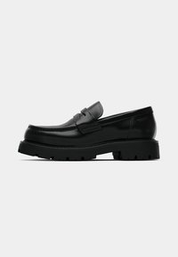 Čierne kožené mokasíny s robustnou podrážkou, detailným prešívaním a klasickým dizajnom penny loafer. Hladký povrch s lesklým finišom.