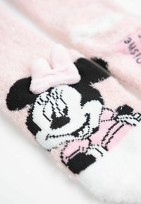 Calze rosa pelose con illustrazione di un personaggio in bianco e nero, adornate da un nastro rosa e modelli a righe a contrasto.