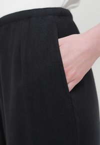 Μαύρο παντελόνι από μαλακό ύφασμα με άνετη εφαρμογή, ελαστική μέση, πλαϊνές τσέπες και διακριτικές πιέτες.