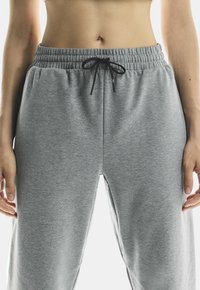 Pantaloni de jogging gri cu elastic la talie, confecționați dintr-un material moale și texturat. Au buzunare laterale și o croială confortabilă.