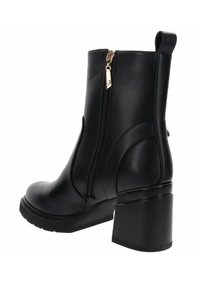 Zwarte enkelboot met een glanzende afwerking, zijrits en een chunky hak. Heeft een gladde textuur en gebogen paneeldetails.