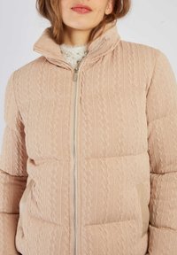 Jasnoróżowa pikowana kurtka wykonana z teksturowanej dzianiny, z wysokim kołnierzem, zapięciem na zamek błyskawiczny oraz beżowymi panelami bocznymi.