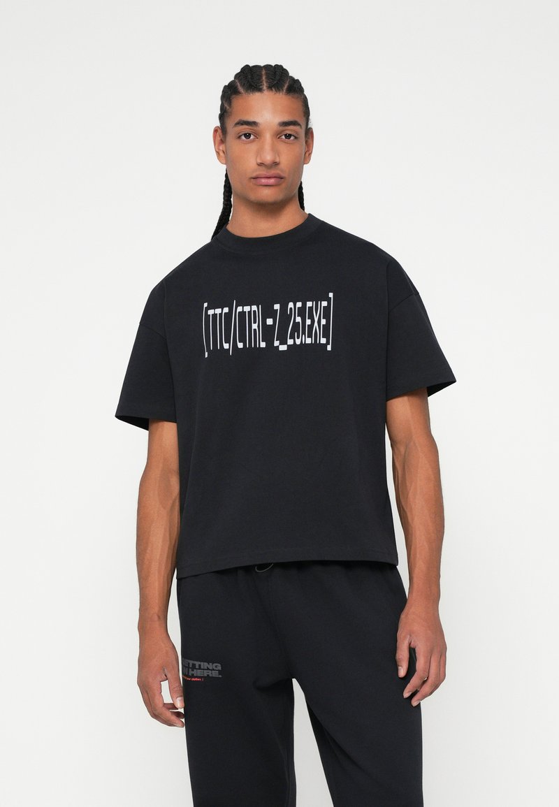Μαύρη κοντομάνικη μπλούζα φτιαγμένη από βαμβάκι, με άσπρη γραφιστική εκτύπωση "[TTC/CTRL-Z.25.EXE]" μπροστά και άνετη γραμμή.