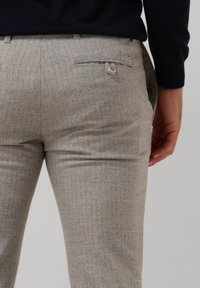 Light gray tailored trousers with a subtle check pattern, featuring a single back pocket and a zip fly. Textured fabric with a clean finish.
