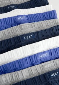 Set aus acht Paar elastischen Shorts in verschiedenen Farben: marineblau, weiß, grau, hellblau, dunkelblau, jeweils mit "NEXT"-Labels in kontrastierenden Farbtönen.
