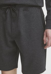 Mørkegrå shorts laget av teksturert stoff, med elastisk midje og snøring, samt sidelommer for oppbevaring.