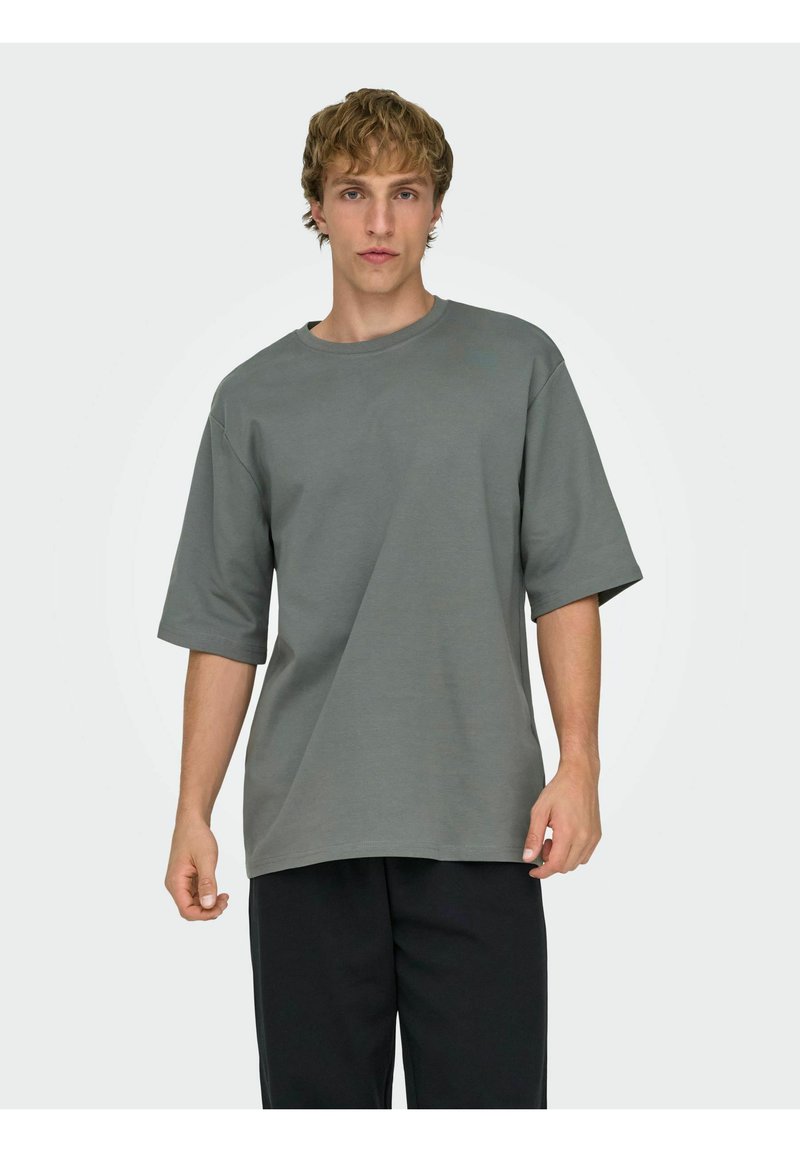 Grijs T-shirt met korte mouwen en ronde hals, gemaakt van katoen; comfortabele pasvorm; gladde textuur; gecombineerd met zwarte broek.