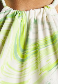 Top halter de tecido leve com um padrão em espiral verde e branco. Apresenta decote drapeado e alças finas ajustáveis. Textura ventilada.