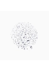 Gotas de agua claras de diferentes tamaños agrupadas en un patrón circular sobre una superficie lisa y blanca.