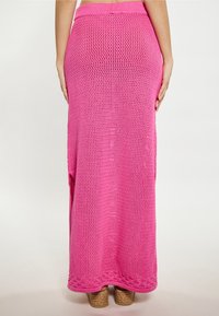 Fustă maxi tricotată lungă, de culoare roz, cu un brâu rib atat, prezentând slituri laterale și un model texturat. Purtați cu pantofi espadrile bej.