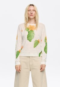 Lichtgewicht, crèmekleurig shirt met lange mouwen en een cactus- en bloemenprint. Heeft een relaxte pasvorm en ribgebreide manchetten. Zachte textuur.