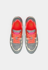 Grå ruskind og tekstil sneakers med koralfarvede snørebånd og accenter, der har en lys grå gummisål og et fremtrædende logo på tungen.