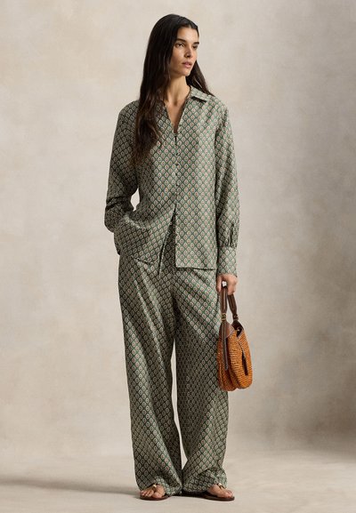 Πράσινα άνετα ρούχα με σχέδια, που περιλαμβάνουν πουκάμισο με γιακά και παντελόνια με φαρδιά μπατζάκια. Το ύφασμα έχει απαλή υφή και λουλουδένια μοτίβα. Κρατείται μια πορτοκαλί τσάντα.