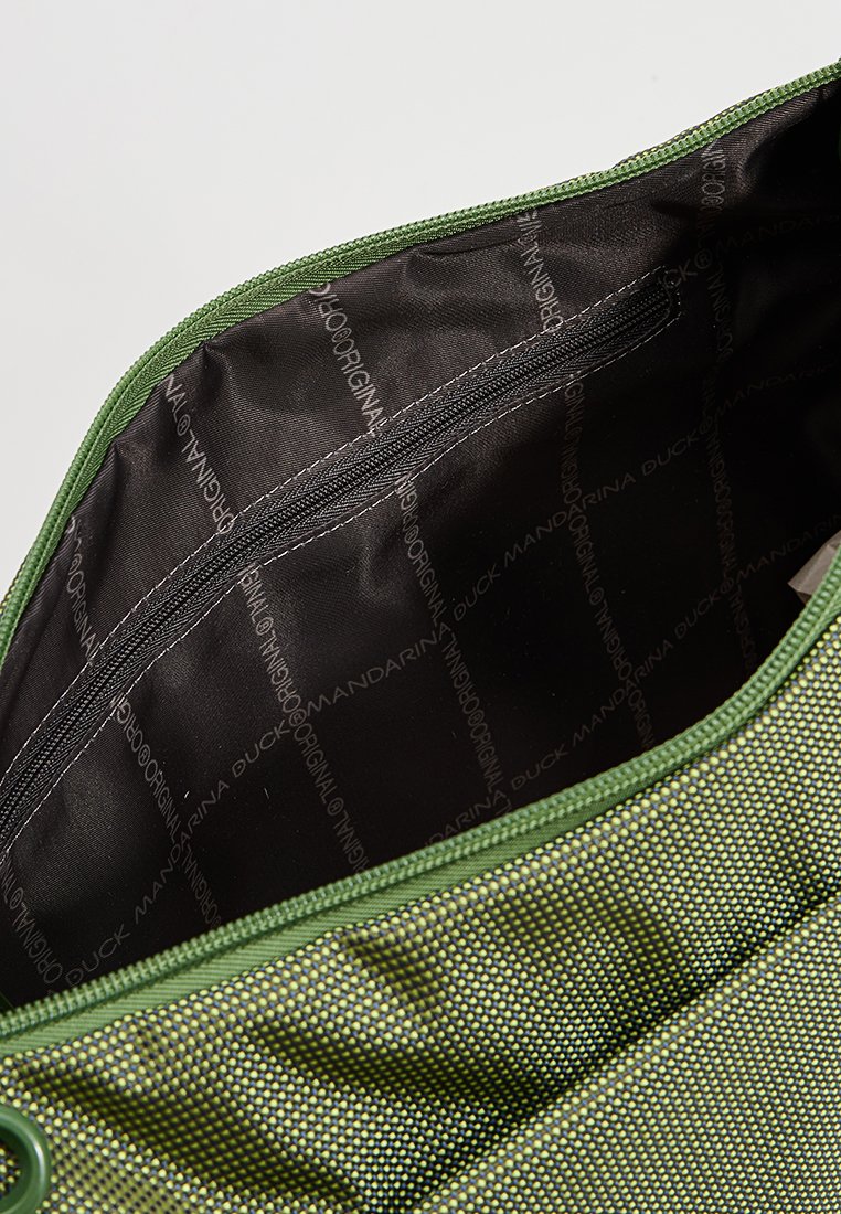 Interior de una bolsa de tela verde con un patrón texturizado de puntos. Presenta un bolsillo con cremallera y un forro negro con el logo de la marca en toda su superficie.