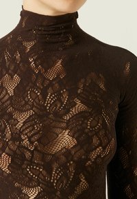Suéter de encaje marrón de manga larga y cuello alto con patrones florales texturizados. Presenta un ajuste ceñido y un cuello alto, revelando la piel por debajo.