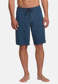 Pantaloni corti blu con vita regolabile tramite cordino, cuciture a contrasto, logo inciso e lunghezza fino a metà coscia. Realizzati in tessuto a asciugatura rapida.