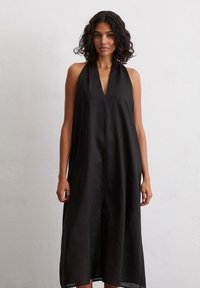 Schwarzes Trägerkleid mit tiefem V-Ausschnitt, aus leichtem Material gefertigt, mit einer lockeren, fließenden Silhouette und knielanger Länge.