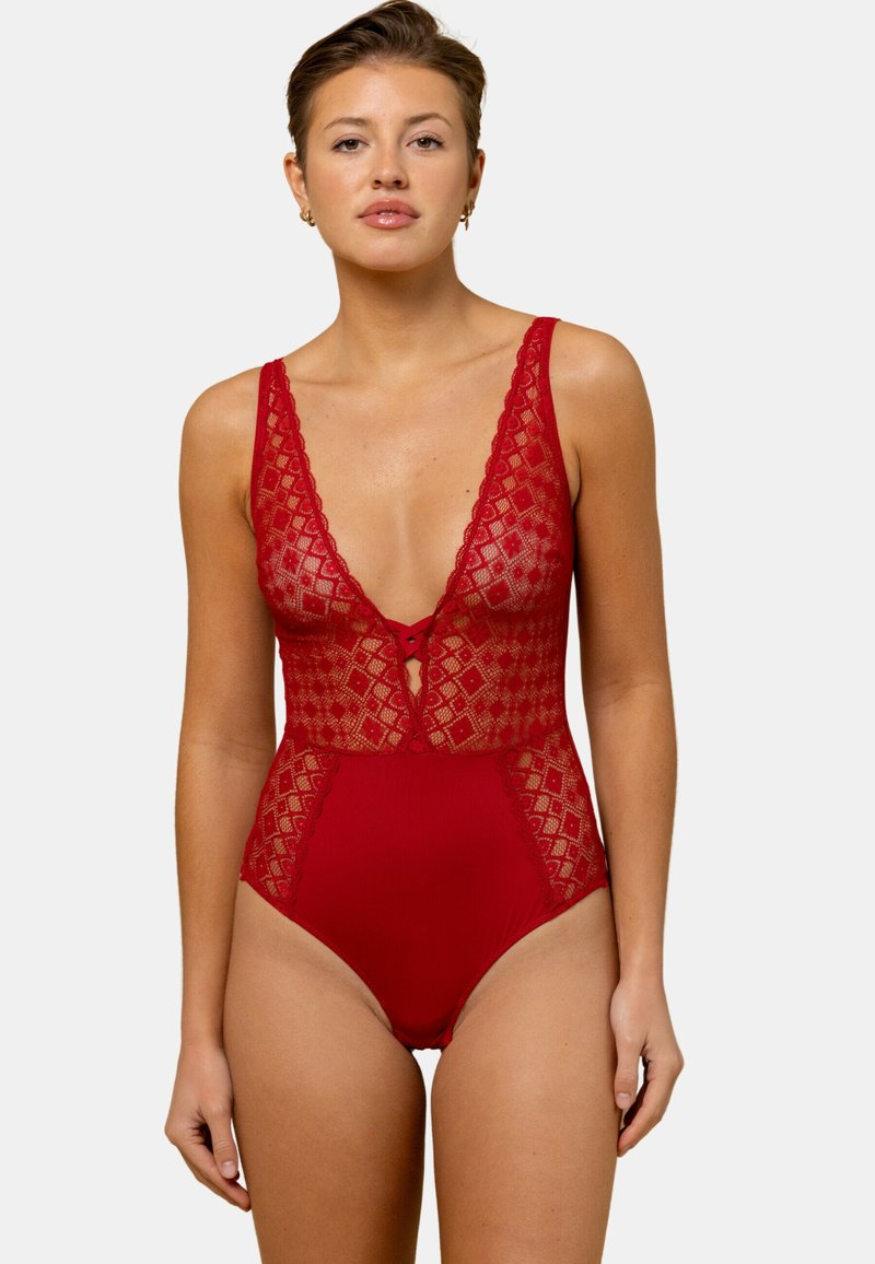 Bodysuit rouge avec un décolleté en V profond, un revêtement en dentelle avec des motifs en diamant et un bas ajusté. Conçu avec des bretelles fines et un devant à nouer.