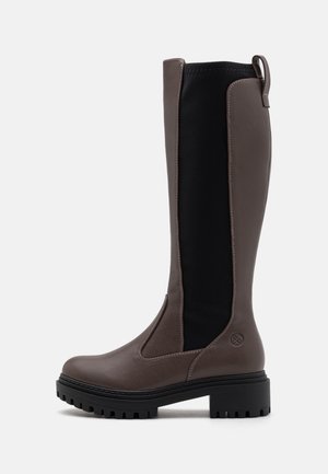 Botte haute en cuir marron avec panneau latéral élastique noir, semelle crantée, petit talon épais et languette à l'arrière, vue de côté sur fond blanc.