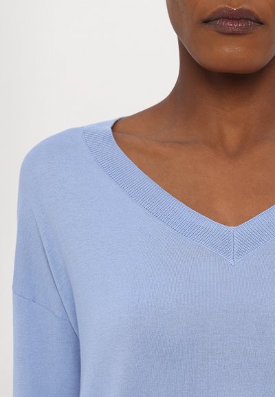 Maglione lavorato a maglia di colore azzurro chiaro con scollatura a V. Presenta una consistenza morbida e una vestibilità rilassata, con dettagli a coste lungo il collo.