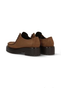Zapatos de ante marrón con puntera redondeada, suelas de goma marrón gruesa para tracción y detalles en cordones. Textura suave con costuras visibles.