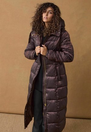 Manteau en duvet long, brun foncé, avec un design matelassé et une capuche. Doté de fermetures éclair et de boutons dorés, de poches avant et d'une texture brillante.