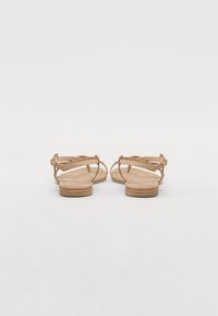 Tan semskede sandaler med justerbare stropper, flate tresåler og et minimalistisk design. Lukket bak og dekorative sømdetaljer.