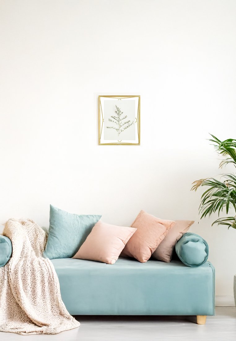 Canapé turquoise avec des pieds en bois clair, deux accoudoirs ronds et un rembourrage doux. Quatre coussins : deux en bleu clair, deux en pêche doux. Plaid beige confortable.