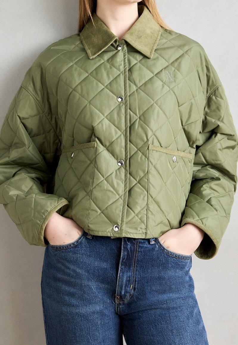 Quilted grøn jakke med en kordfløjlskrave, trykknapper og forlommer. Har en boxy fit med struktureret stof og en kort længde.