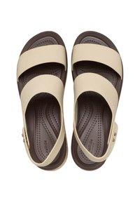 Sandalias beige con dos correas anchas cruzando el pie, plantilla texturizada en marrón y hebilla lateral ajustable para un mejor ajuste.