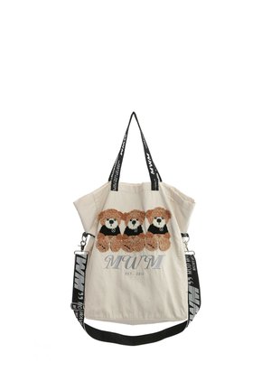 Bolsa tote beige con tres ositos de peluche marrones que llevan camisetas negras y una correa de hombro y asas de marca en blanco y negro.