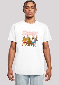 Hvit bomulls t-skjorte med fargerike tegneseriefigurer fra "Scooby-Doo," med en dristig grafisk trykk på forsiden. Standard passform.