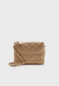 Prošívaná béžová kožená crossbody kabelka s vyraženým logem "Valentino", obdélníkový tvar, nastavitelný popruh a zipové uzavření.