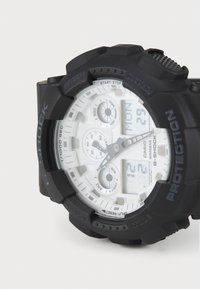 Black resin G-Shock watch with a white dial, featuring digital and analog displays, three sub-dials, and textured push buttons.