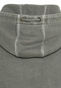 Gray hoodie with a drawstring neck, featuring a kangaroo pocket and soft, textured fabric. Stitching visible along the seams.