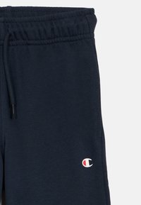 Παντελόνι φόρμας σε ναυτικό μπλε χρώμα με ελαστική μέση, κορδόνι και μικρό λευκό και κόκκινο λογότυπο στο αριστερό μηρό. Μαλακό, υφασμάτινο με υφή.