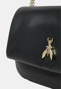 Borsa a tracolla in pelle nera con un flap morbido e curvo. Presenta un emblema d'oro a forma di ape e una tracolla a catena. Texture liscia e design minimalista.