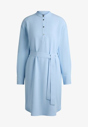 Jasnoniebieska sukienka koszulowa z długimi rękawami, stójką i plisą na guziki z trzema czarnymi guzikami. W komplecie paskiem do związania w talii.